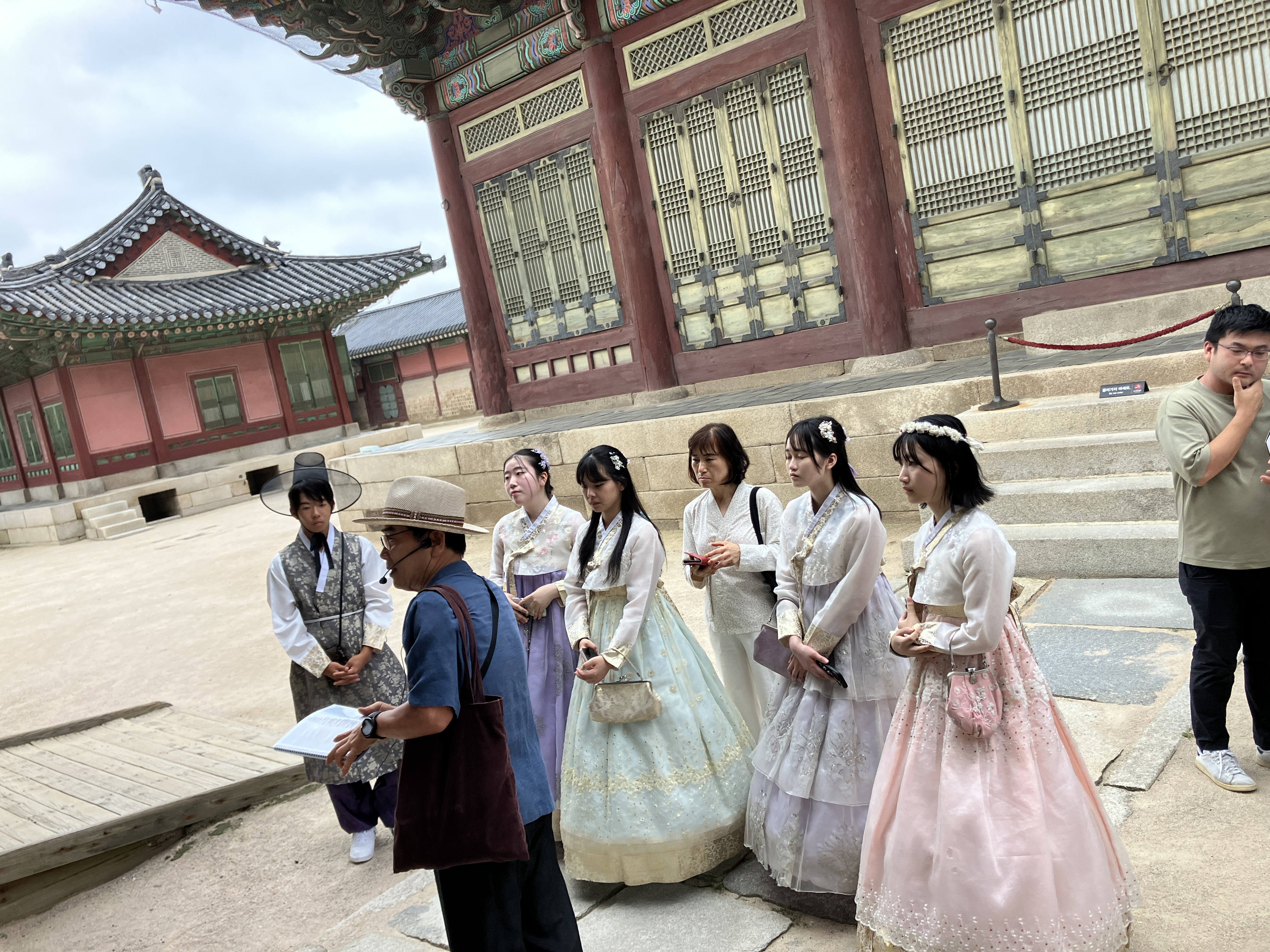 韓国の伝統建築前で参加者が韓服を着て文化体験をする様子
